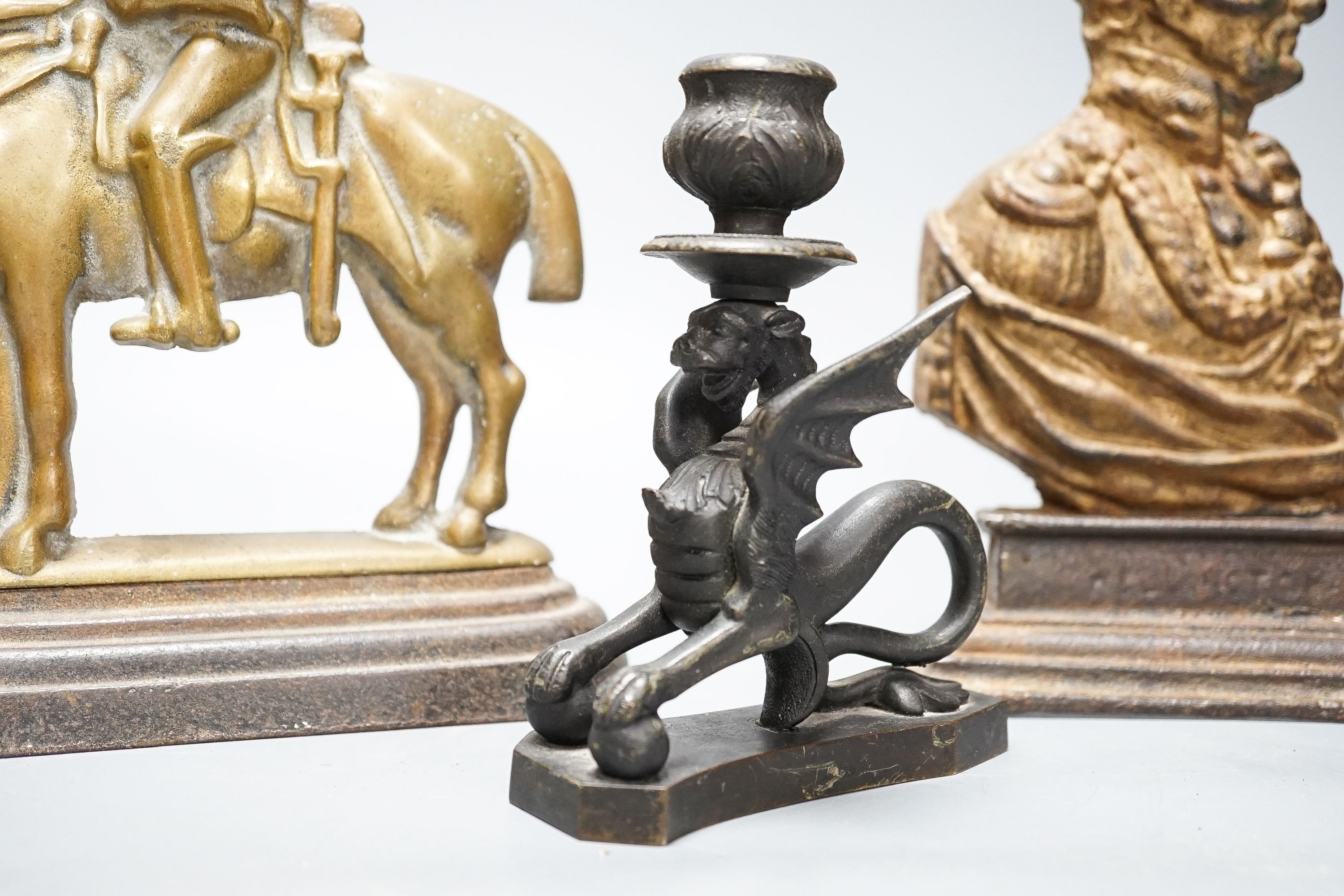 Two brass and cast iron military doorstops and a brass chamberstick 26cm